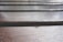 Close-up view of wooden planks with visible grain and texture, arranged horizontally. The lighting highlights the natural pattern and gloss of the wood finish.