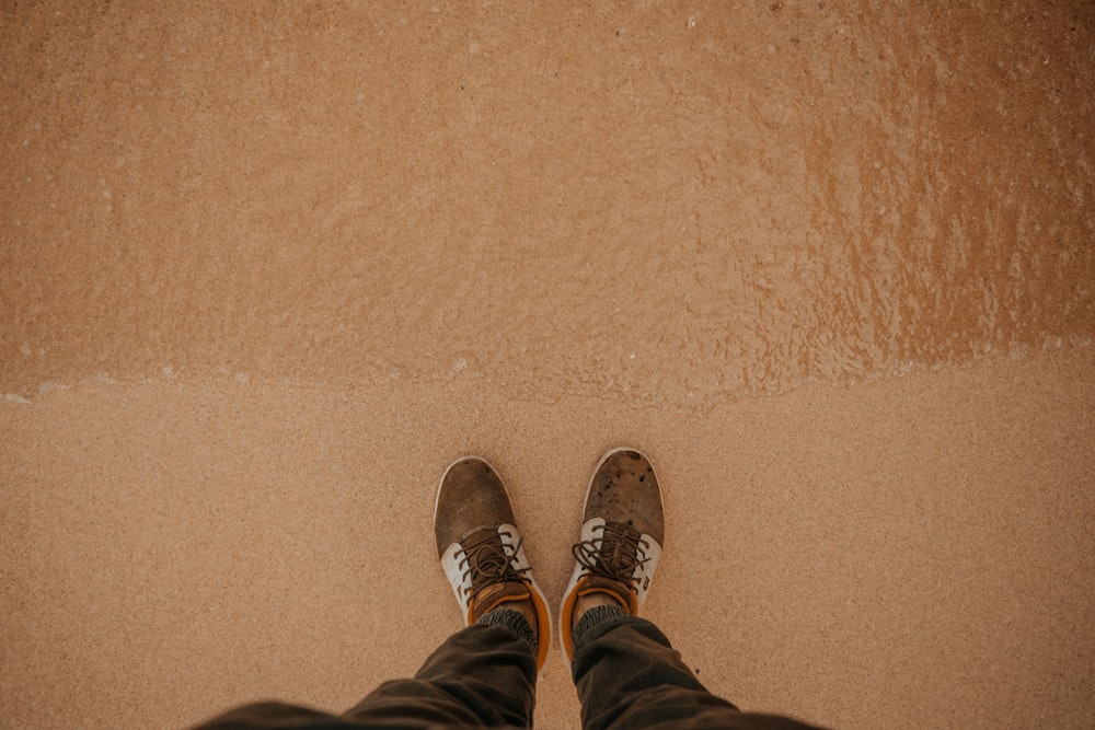 person wear brown low-top sneakers standing on shore