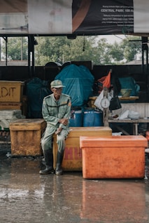 man sitting on yellow fish box during day