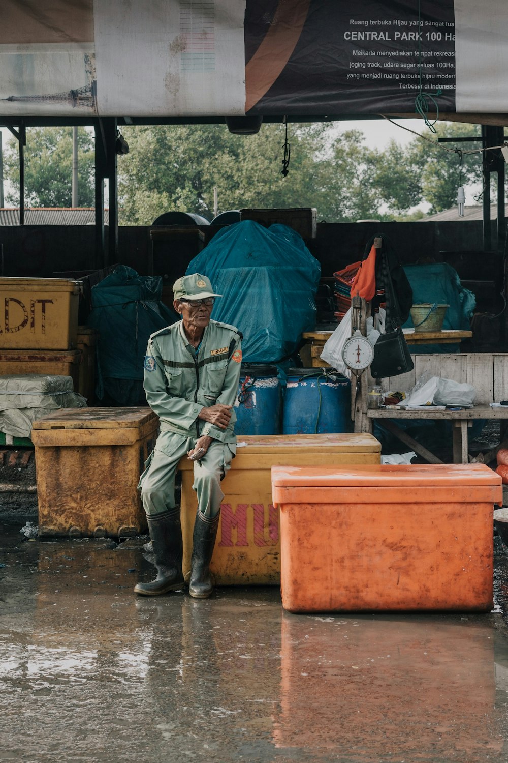 man sitting on yellow fish box during day