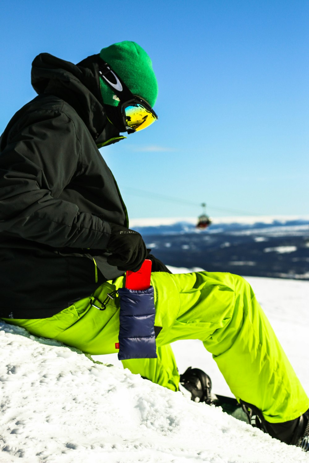 person in black jacket and green pants wearing green snow goggles