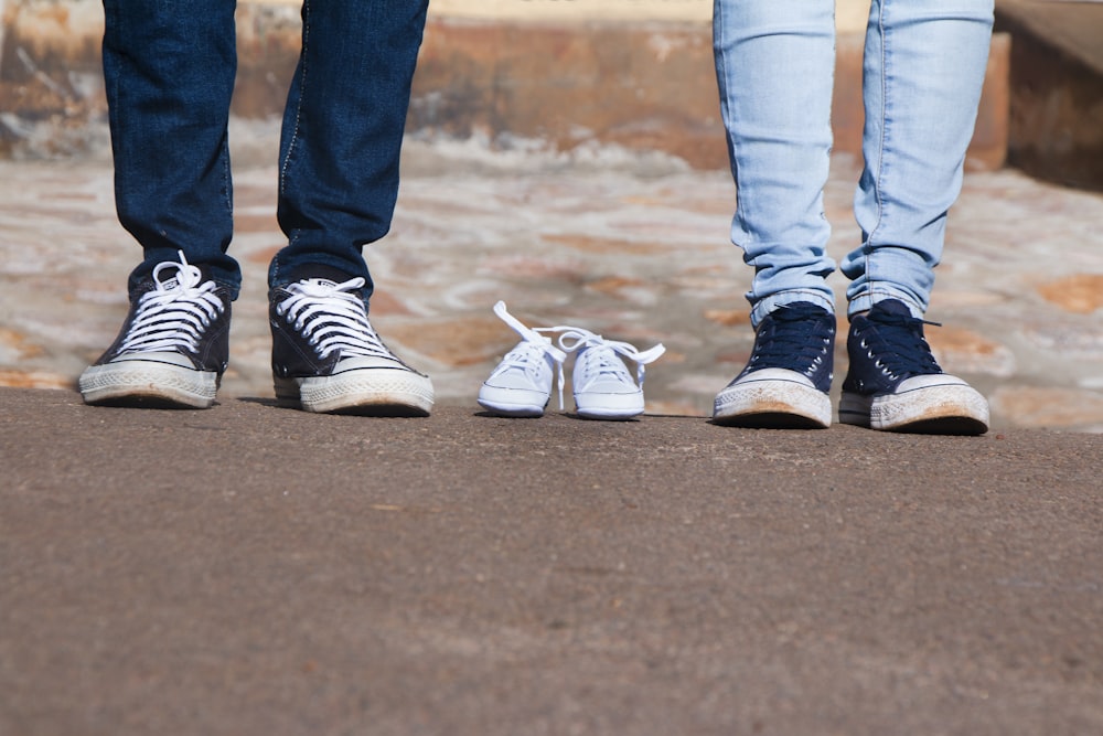 Par de zapatos grises de caña baja entre dos personas que usan jeans