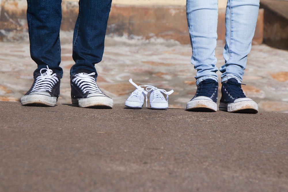 pair of gray low-top shoes between two persons wearing jeans