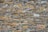 A dry stone wall composed of irregularly shaped stones of varying sizes and colors. The stones are tightly fitted together with no visible mortar, creating a textured and rustic appearance.
