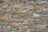 A dry stone wall composed of irregularly shaped stones of varying sizes and colors. The stones are tightly fitted together with no visible mortar, creating a textured and rustic appearance.