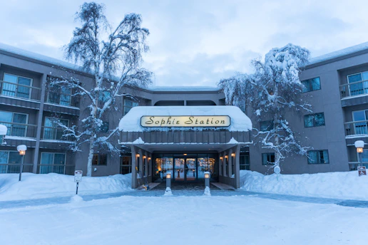 Friendly concierge welcoming guests at a snowy alpine chalet entrance.