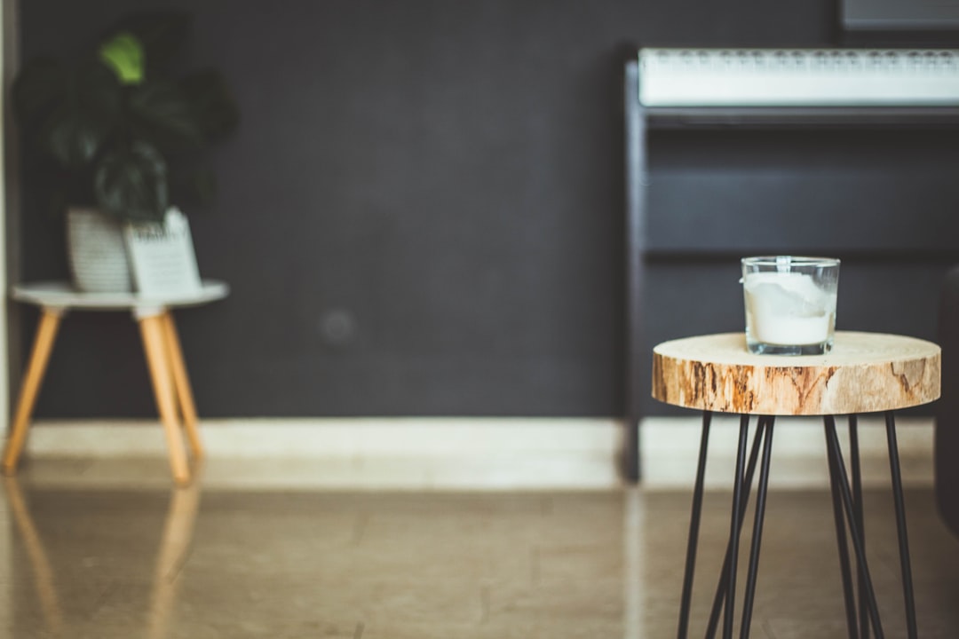 focus photography of white candle on brown wood slab end table inside room