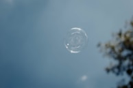 A delicate soap bubble floating against a soft pastel background, evoking 'L’amour est une bulle de savon.'