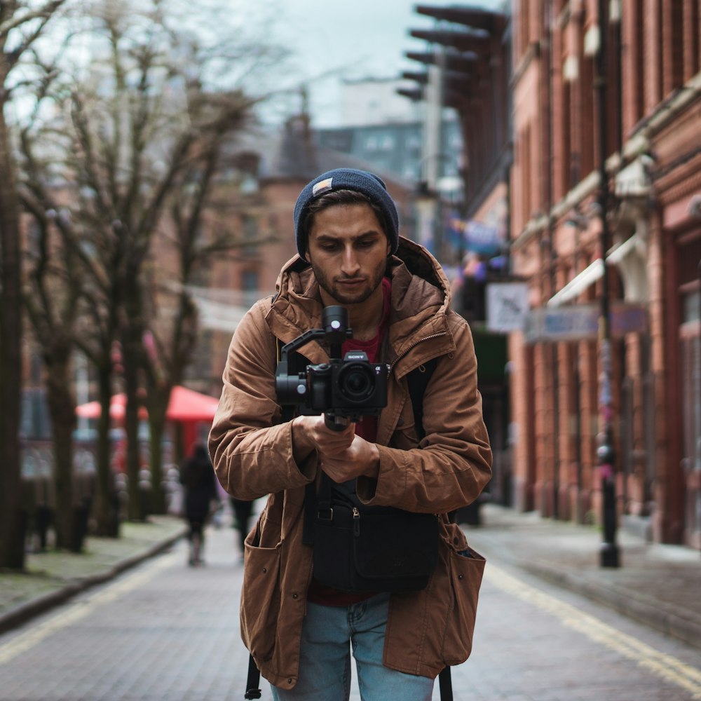 depth of field photography of man holding camera