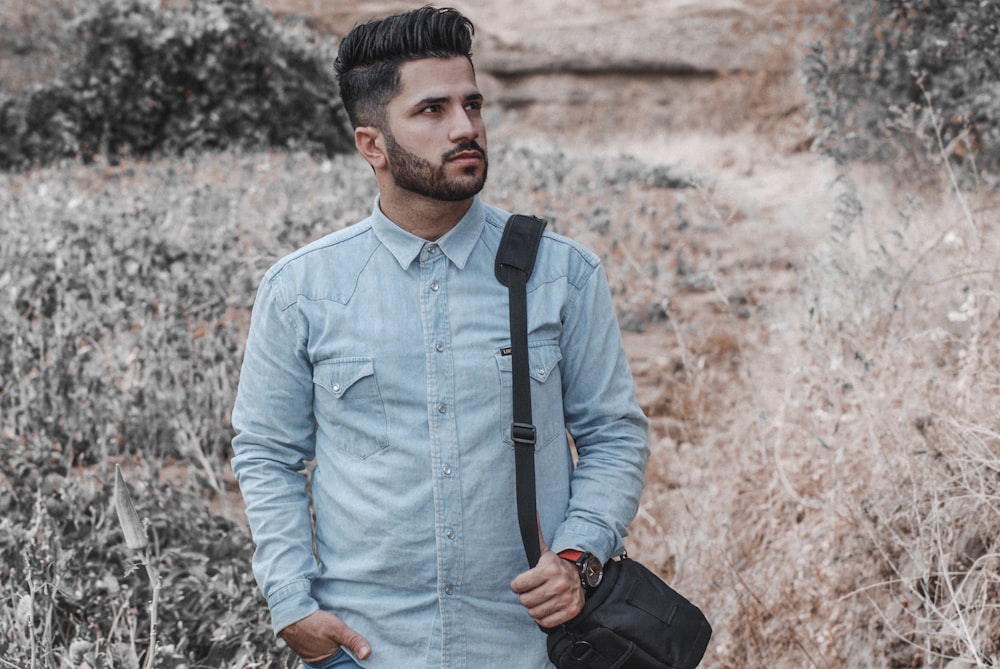 man carrying bag near brown grass during daytime