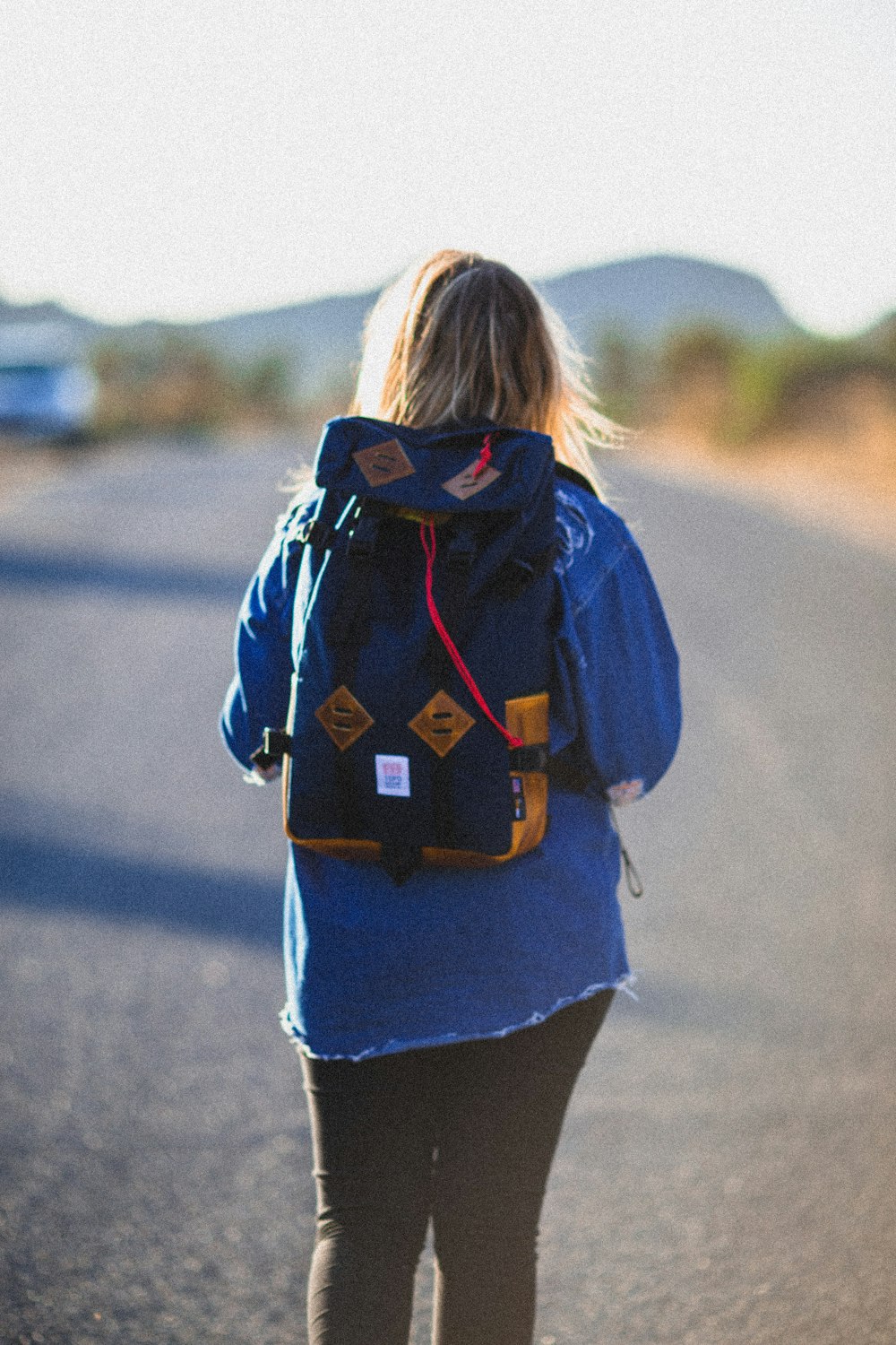 woman wearing blue backpack standing on road