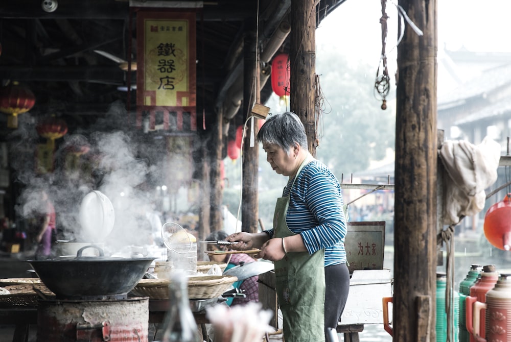 woman in gray apron holding utensil