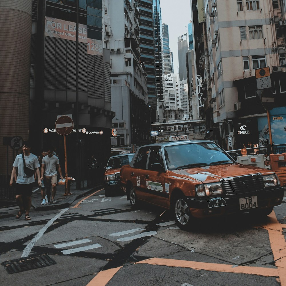 brown car beside man walking in street during daytime