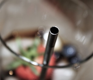 Close-up of shiny metal straws arranged neatly on a wooden table with green leaves around.