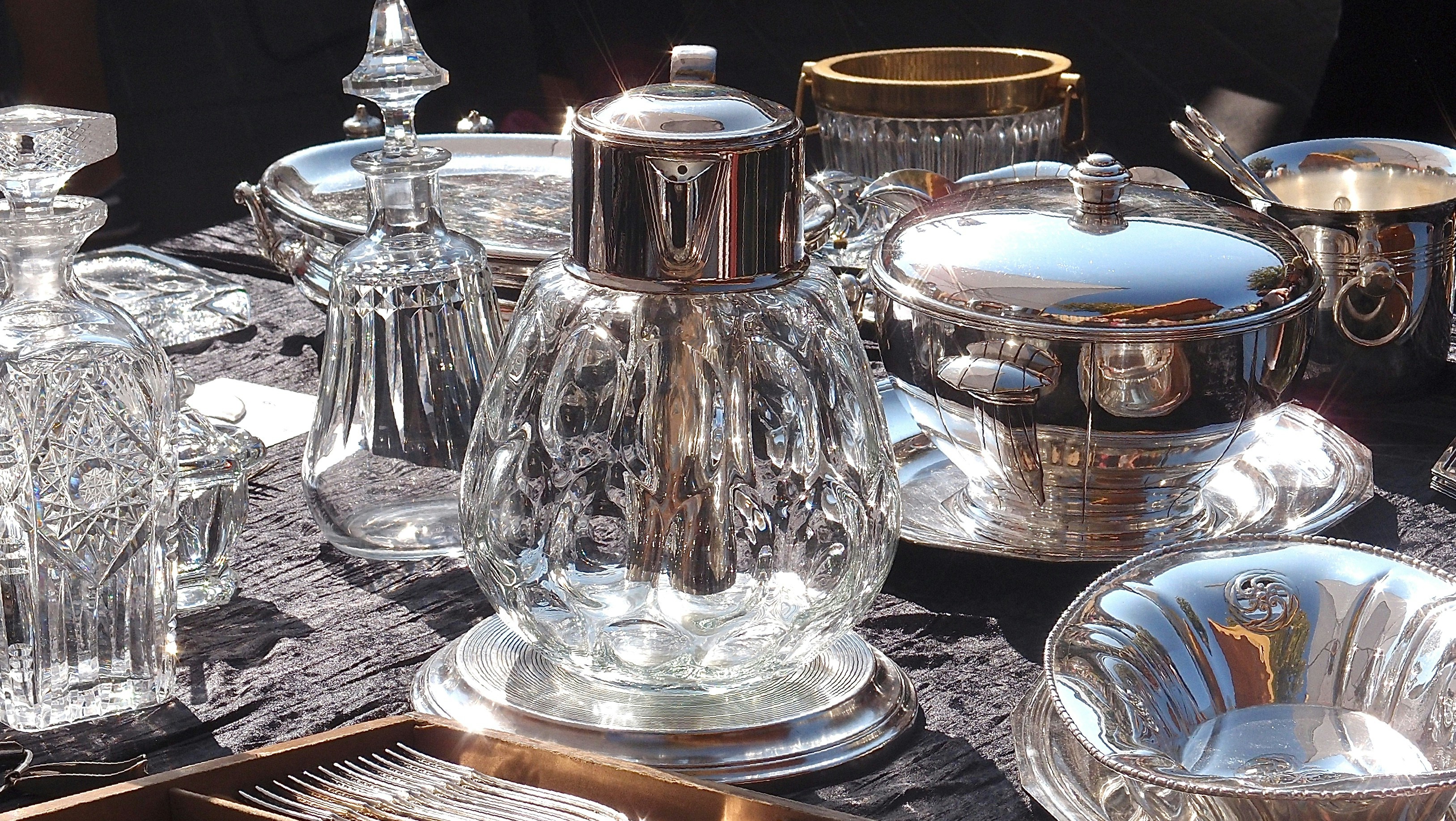 Antique silver tea service set with ornate engraving on dark velvet display surface under bright studio lighting