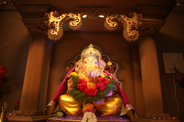 A beautifully crafted Ganesh idol made from natural clay, surrounded by fresh green leaves.