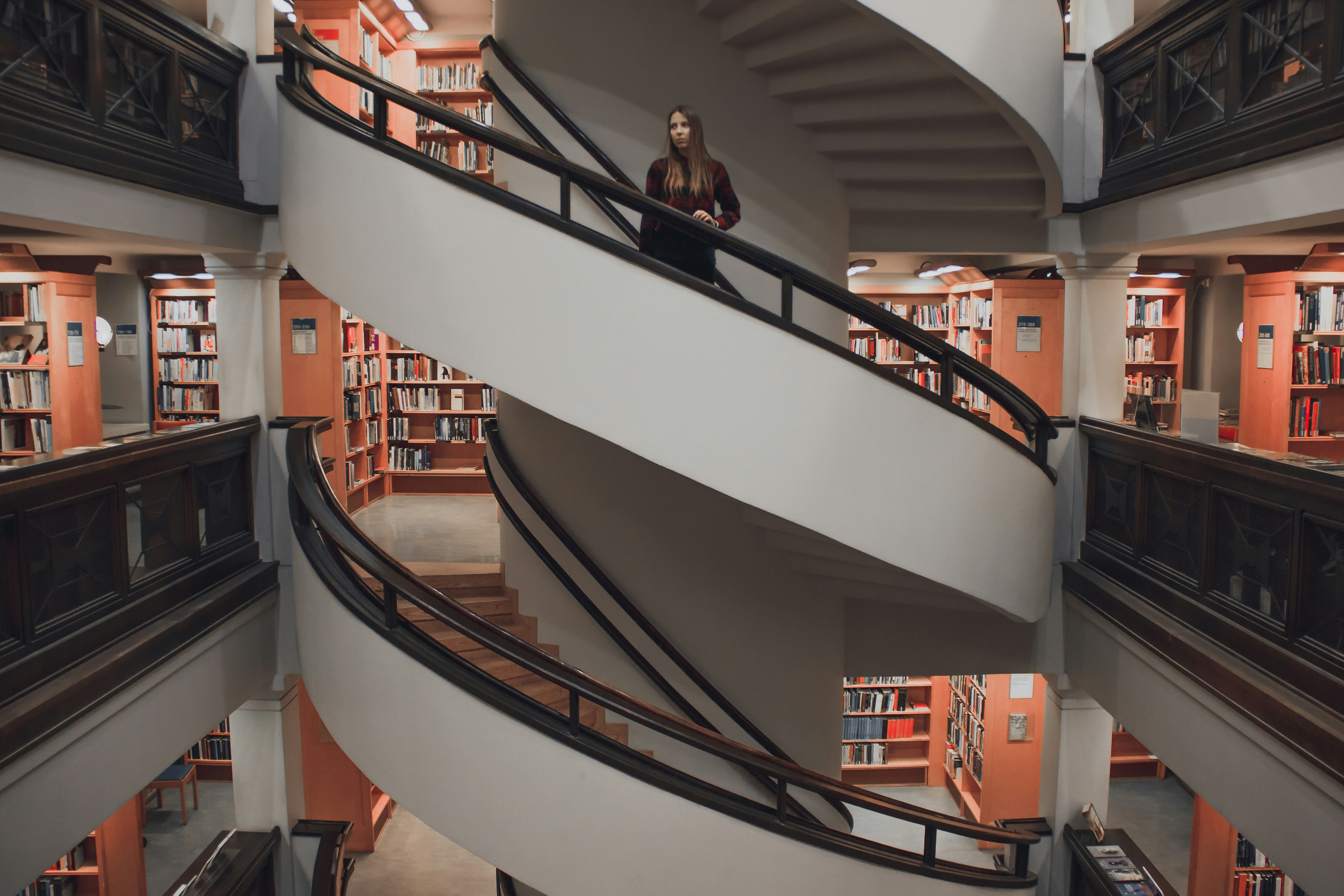 A large contemporary spiral staircase in a library representing the ongoing  journey we take to work through the challenges that make us feel like a fraud.