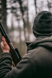 man standing while holding hunting rifle