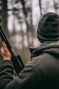 man standing while holding hunting rifle