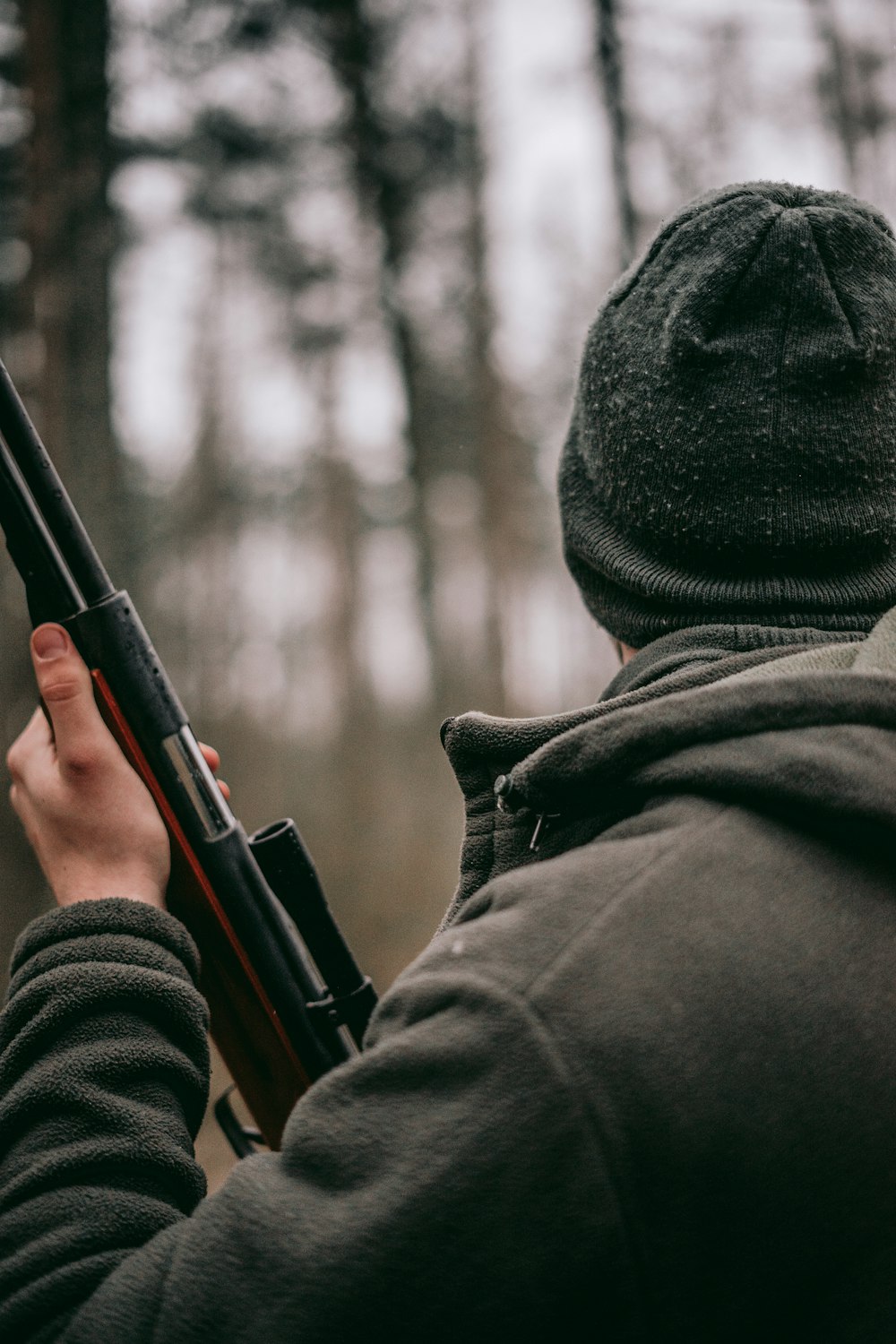 man standing while holding hunting rifle