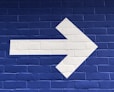 white arrow painted on brick wall