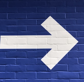 white arrow painted on brick wall