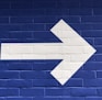 white arrow painted on brick wall