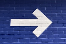 white arrow painted on brick wall