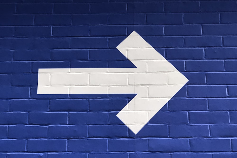white arrow painted on brick wall
