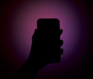 A silhouetted hand is holding a smartphone against a vibrant, gradient background that transitions from deep purple to magenta.