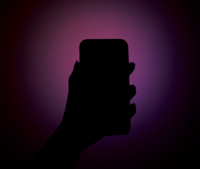 Close-up of a hand holding a phone showing the app’s reflective alignment flow against a dark charcoal background with gold accents.