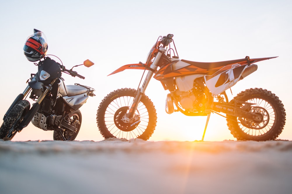 Dos deportes de motor dual negros y naranjas en tierra