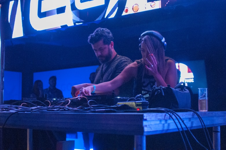 woman playing DJ controller beside man in gray shirt