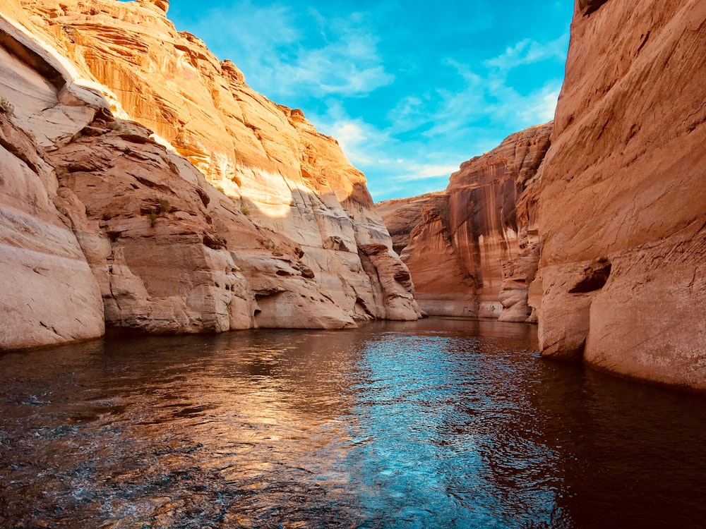 water in the middle of rock formation under blue skies