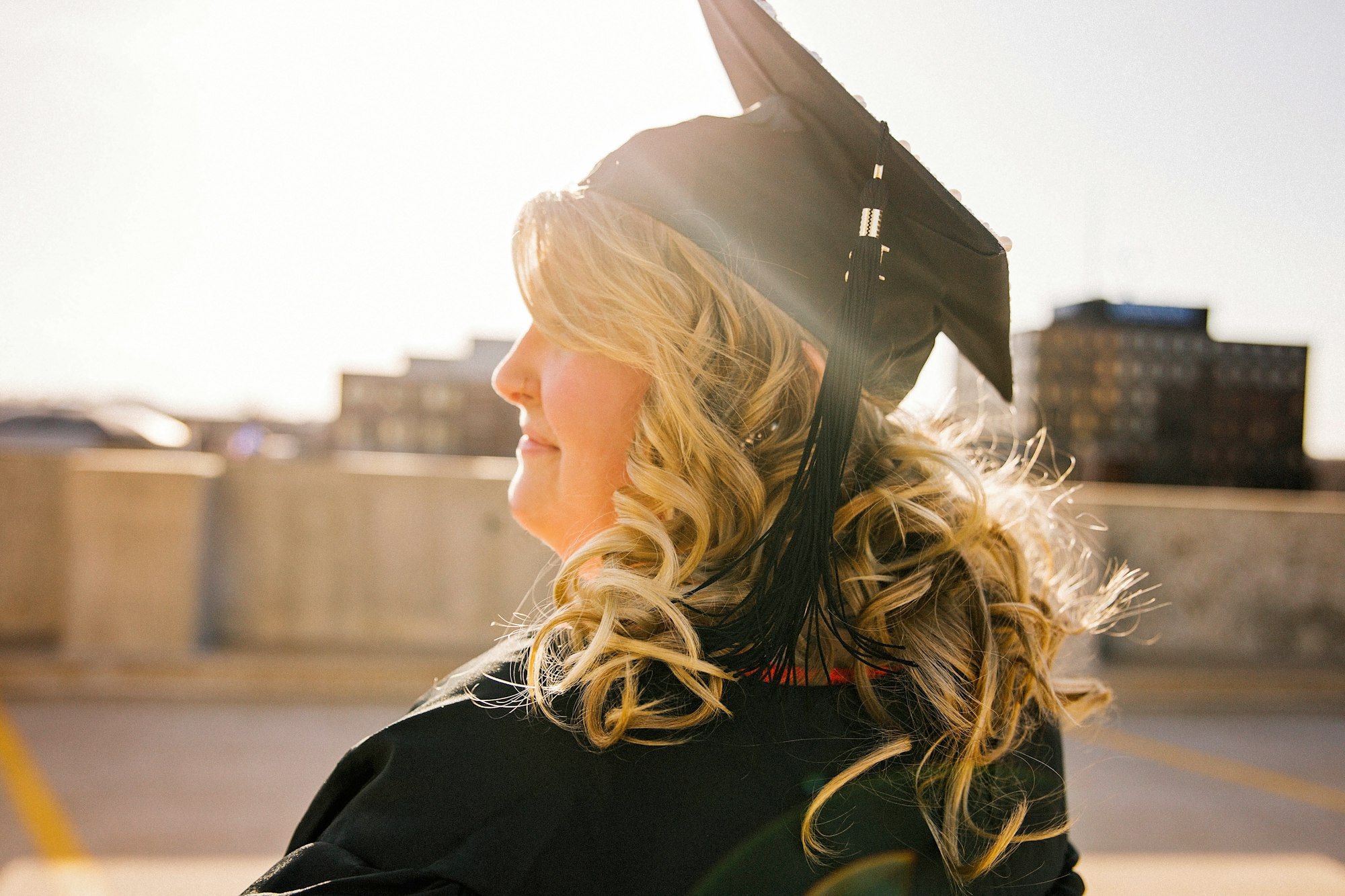 A student on her graduation day looking into the sunset.