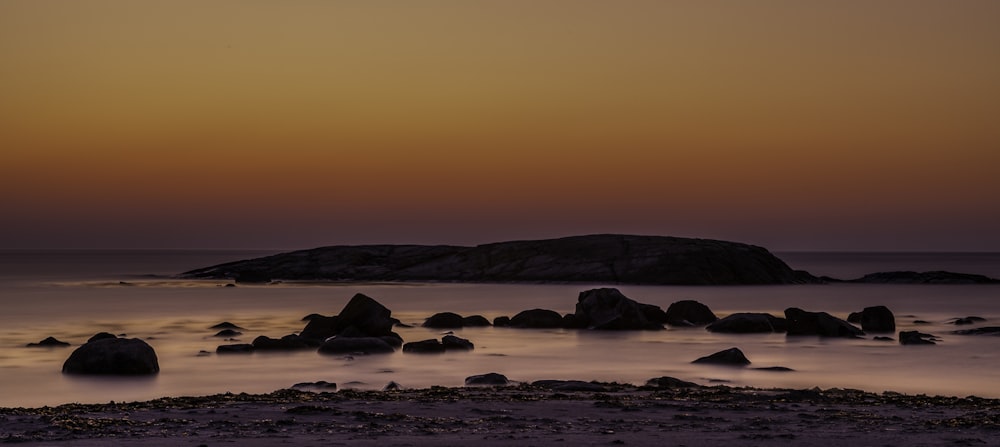 silhouette photography of rock formation in body of water