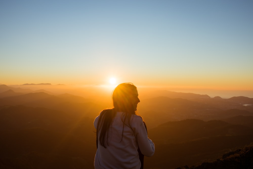 woman sitting while facing sunset