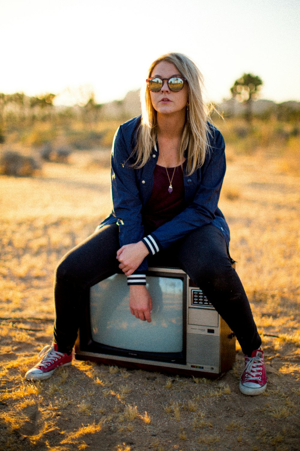 woman wearing blue jacket sitting on CRT TV