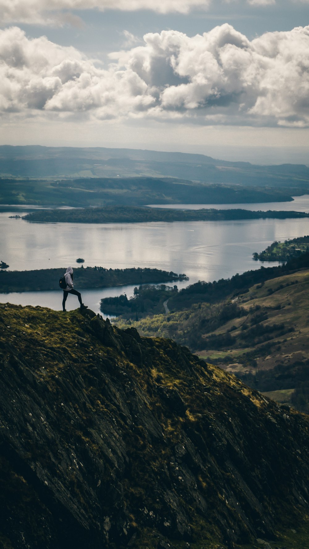 person in gray hooded jacket standing on mountain during day time