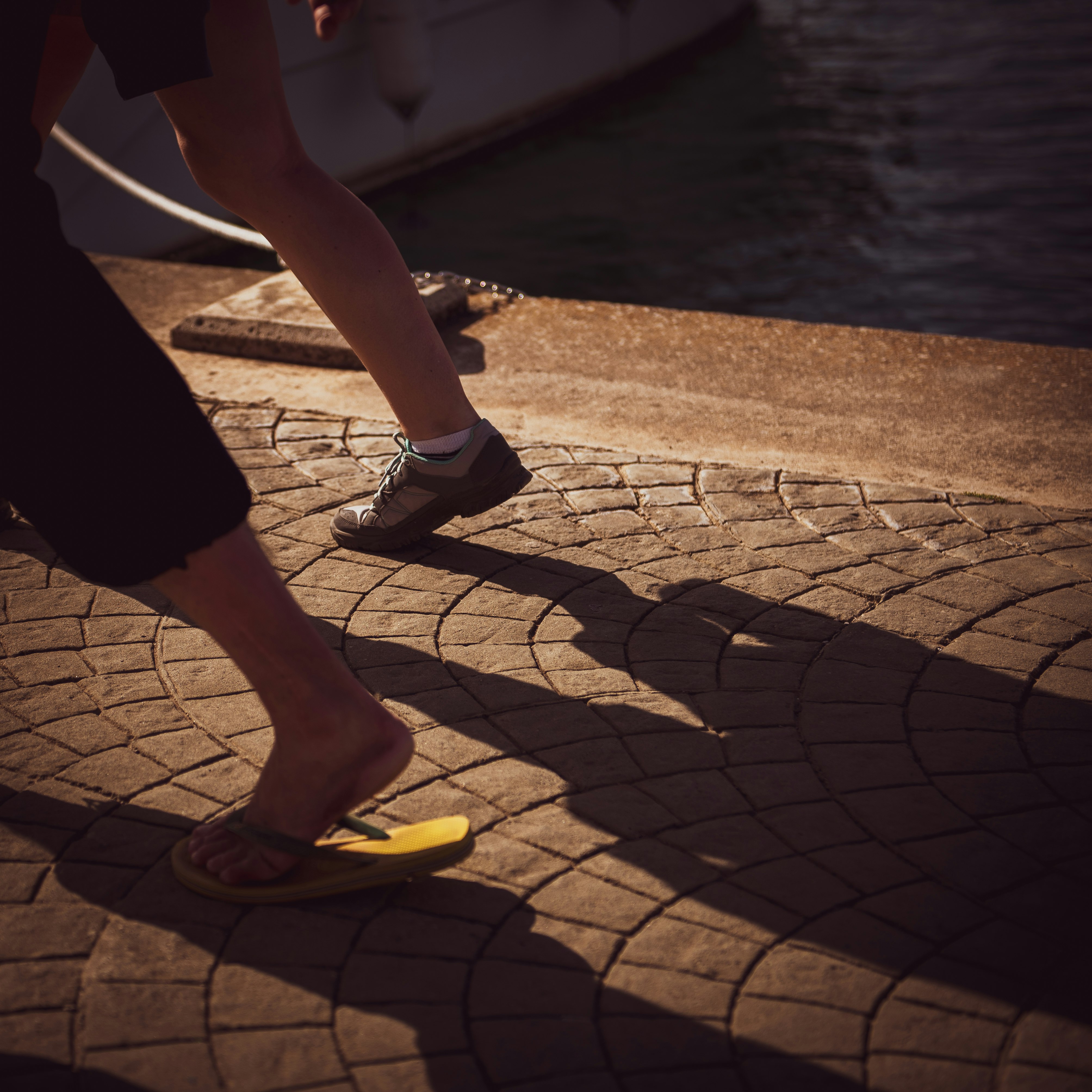 two persons wear slippers and shoes run near harbor