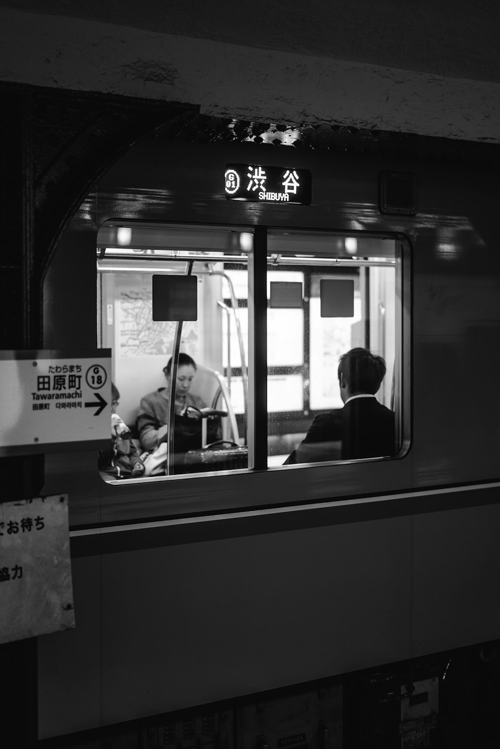 grayscale photo of two people sitting in train