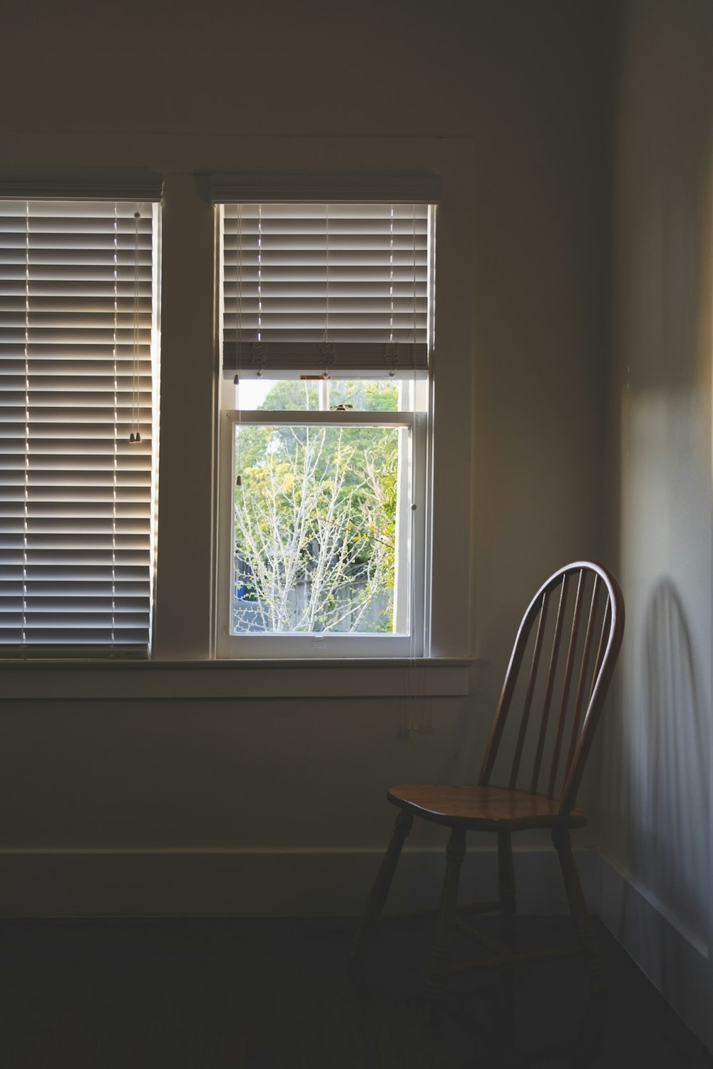 Silla de madera marrón junto a una ventana de vidrio transparente