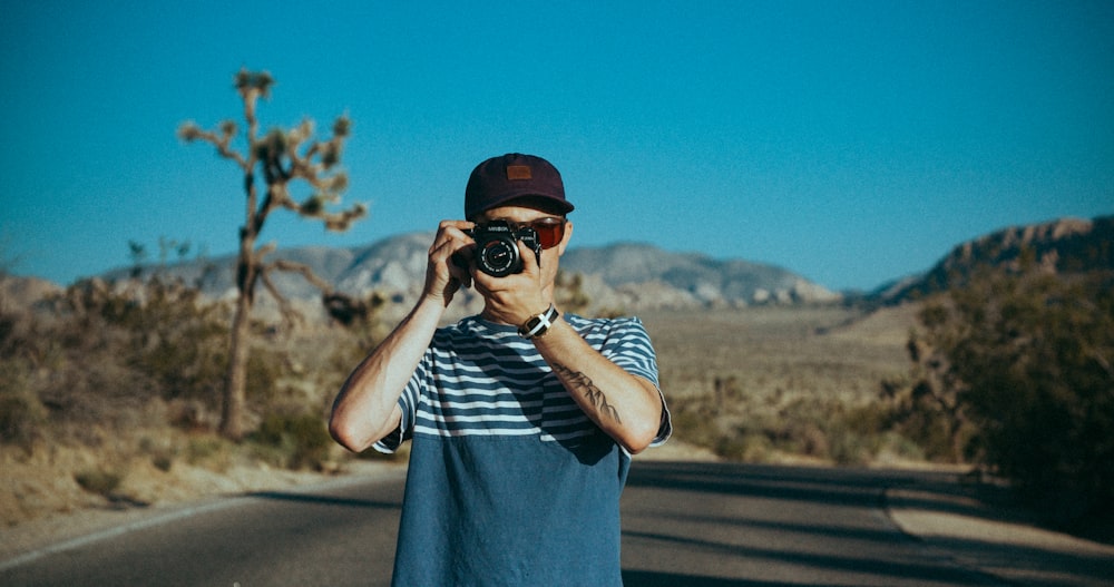 man in crew-neck shirt standing in the middle of road while taking photo