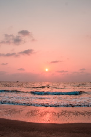 Peaceful sea view at sunset with gentle waves and soft warm light.