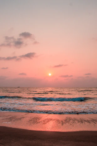 A serene beachfront view at Ocean Dream Resort during sunset, with gentle waves lapping the shore.