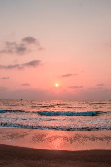 A serene view of the Opal Coast at sunset with gentle waves lapping the shore.