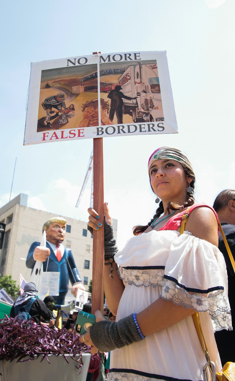 Femme manifestant en tenant des panneaux imprimés No More False Borders