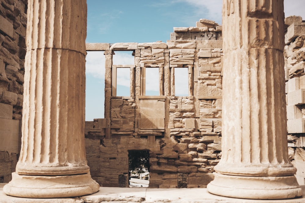 deux colonnes brunes devant des ruines