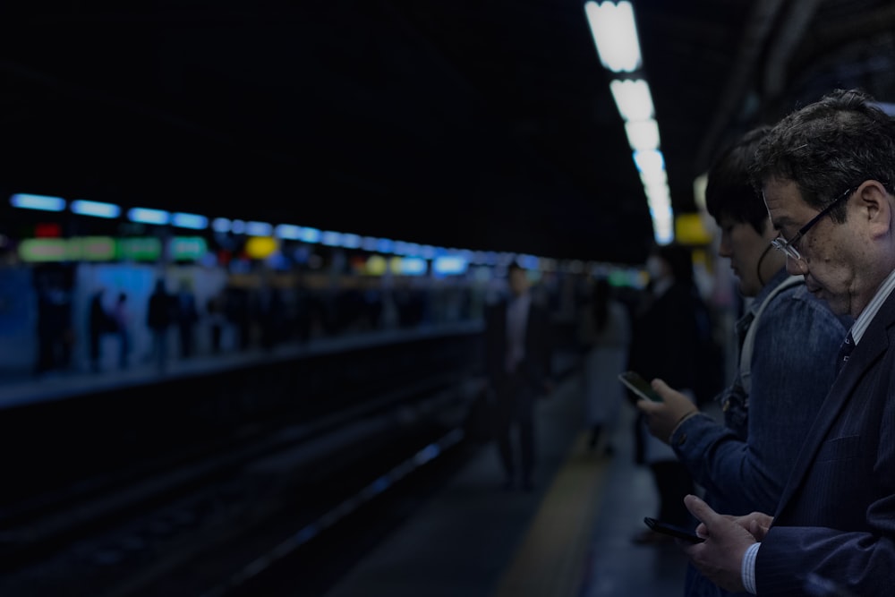 hombre esperando el tren blanco sosteniendo un teléfono celular