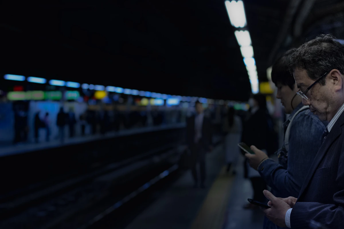 A passenger looking at a smartphone on a station platform